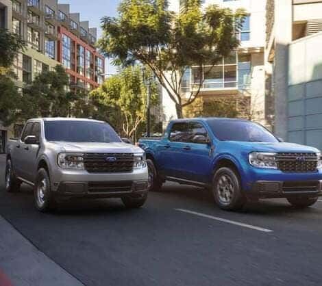 Two Ford vehicles driving side by side down the road in a city