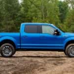 A blue 2019 Ford F-150 Lariat is shown from the side parked in front of a line of trees after leaving a used Ford dealership.