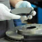 A mechanic is shown holding up a brake pad at an auto repair shop near McDonough.