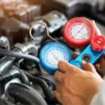 A mechanic checking a vehicle's AC system at an auto repair shop near Stockbridge.