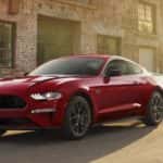 A red 2022 Ford Mustang is parked on the side of a city street after viewing used cars for sale.
