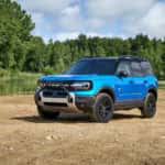 A blue 2025 Ford Bronco Sport Badlands Sasquatch parked off-road near water.