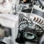 A close up of a mechanic doing an alternator replacement at a repair shop.