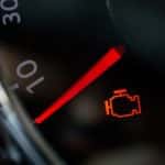 Close-up of a check engine light illuminated on a dashboard.