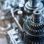 A close up shows transmission gears and a fork during a transmission repair.