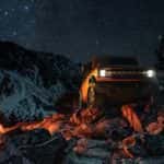 A popular used Ford Bronco for sale, a orange 2022 Ford Bronco, is shown from the front parked in the mountains at night.