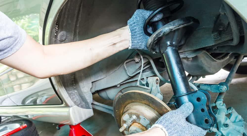 A mechanic is shown removing a strut.