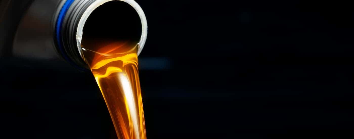 Oil being poured out of a grey bottle during an oil change.