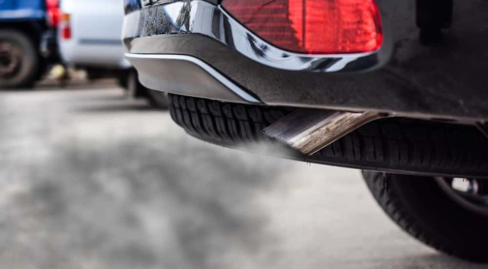 Dark fumes are shown exiting an exhaust pipe.