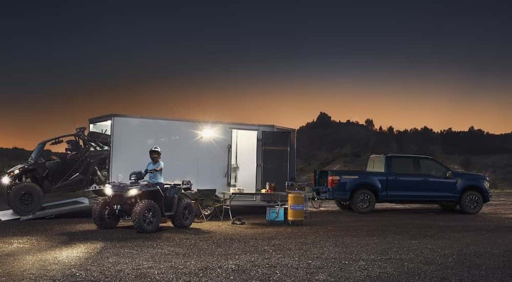 A blue 2025 Ford F-150 Tremor towing a trailer off-road.