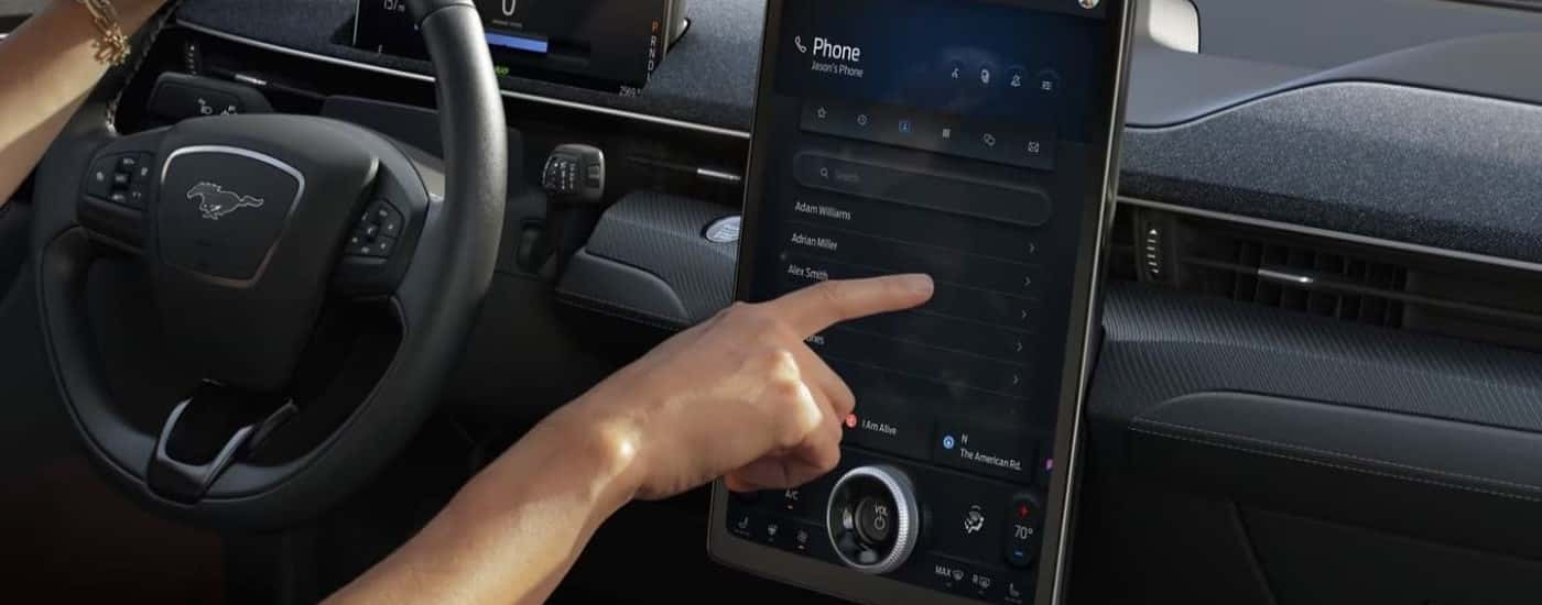 Someone using the infotainment screen in a 2025 Ford Mustang Mach-E.