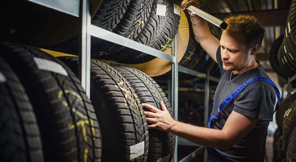 A technician holding a light and looking at a tire.