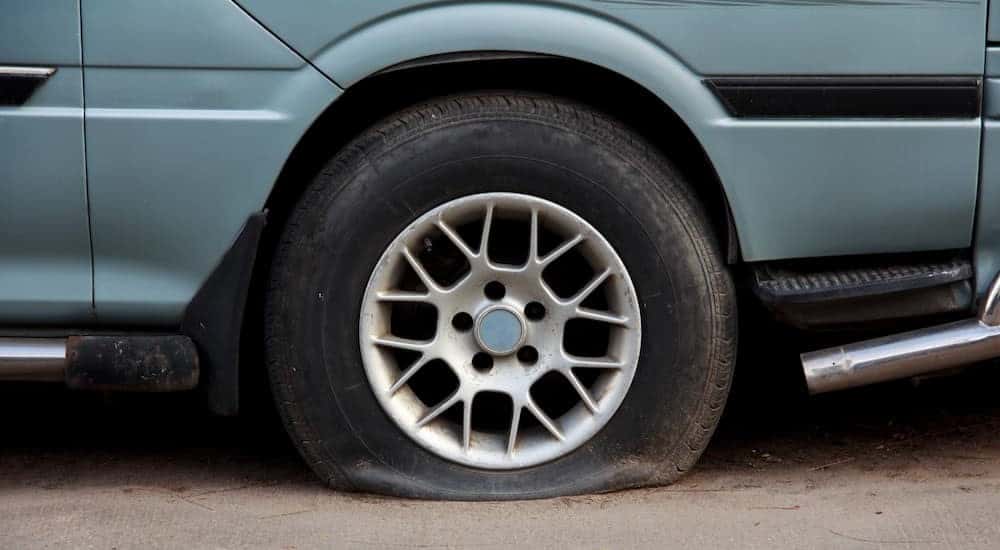 A blue vehicle with a flat tire.