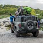 A green 2025 Ford Bronco off-road carrying kayaks on its roof rack