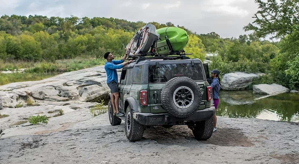 A green 2025 Ford Bronco off-road carrying kayaks on its roof rack