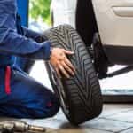 A technician putting a tire on a white car