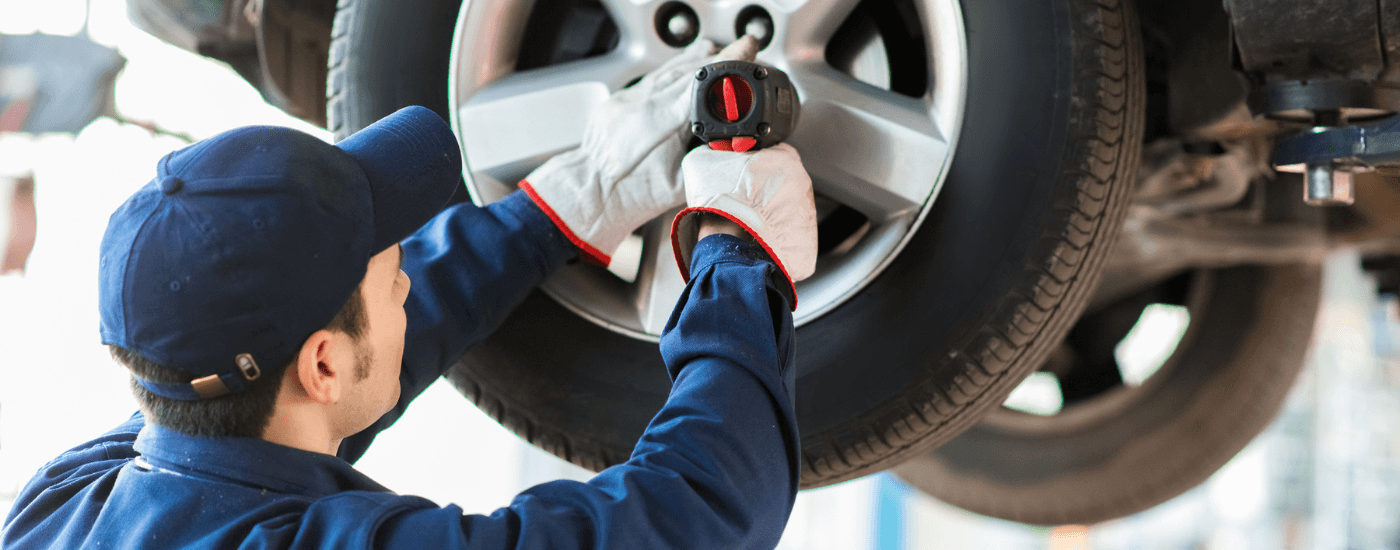 An auto technician putting tires on a vehicle