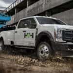 A white 2025 Ford F-350 Super Duty towing a trailer on a construction site.