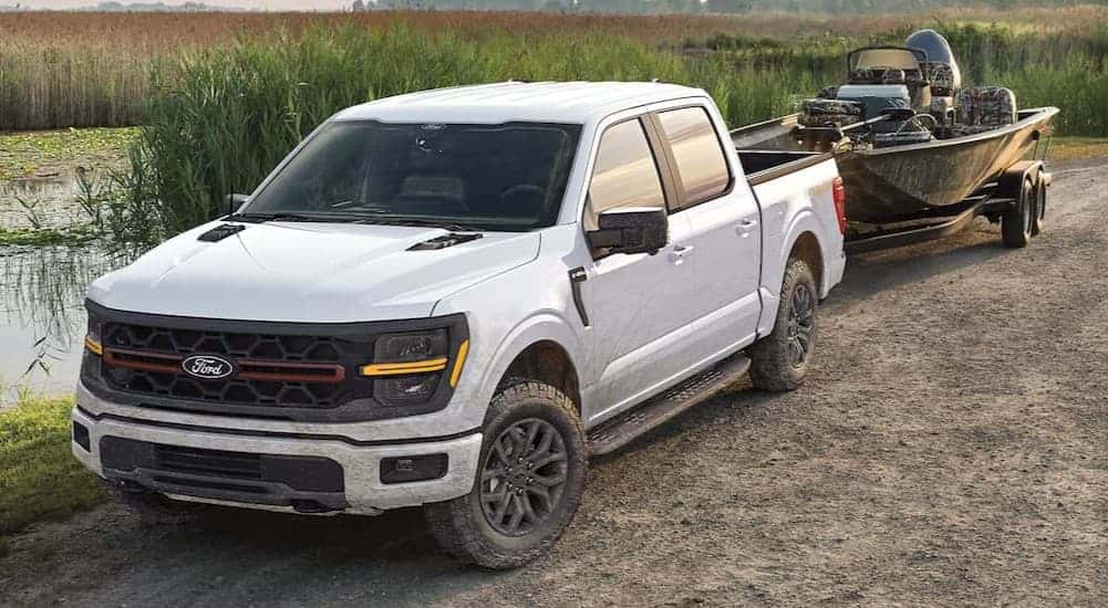 A white 2025 Ford F-150 towing a boat.
