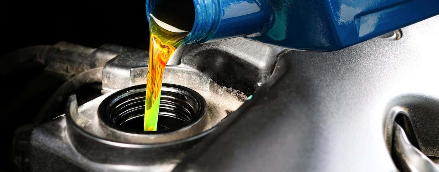 Oil in a blue bottle pouring into an engine