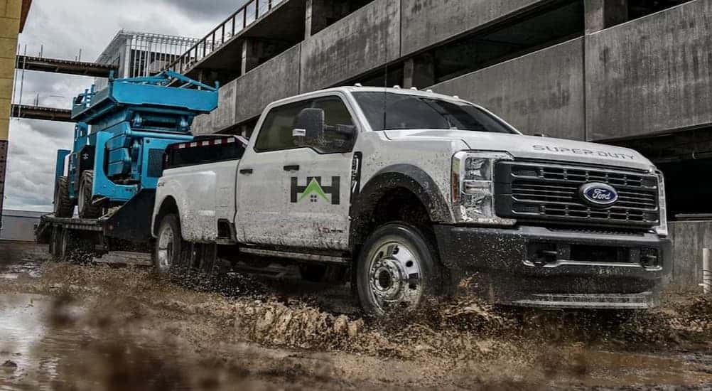A white 2025 Ford F-350 towing a trailer on a construction site.
