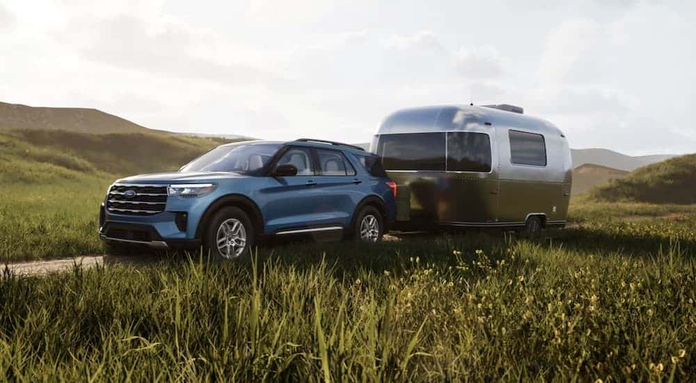 A blue 2025 Ford Explorer Active for sale in Loganville towing a trailer.