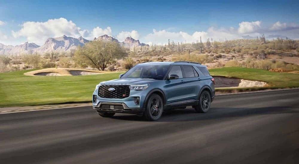 A blue 2025 Ford Explorer ST driving near a golf course.