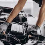A car tech works under the hood of a car showing transmission rear near Snellville.