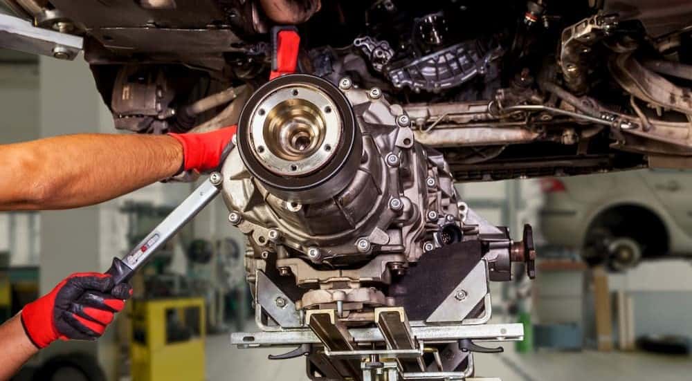 A technician removing a transmission from a vehicle.
