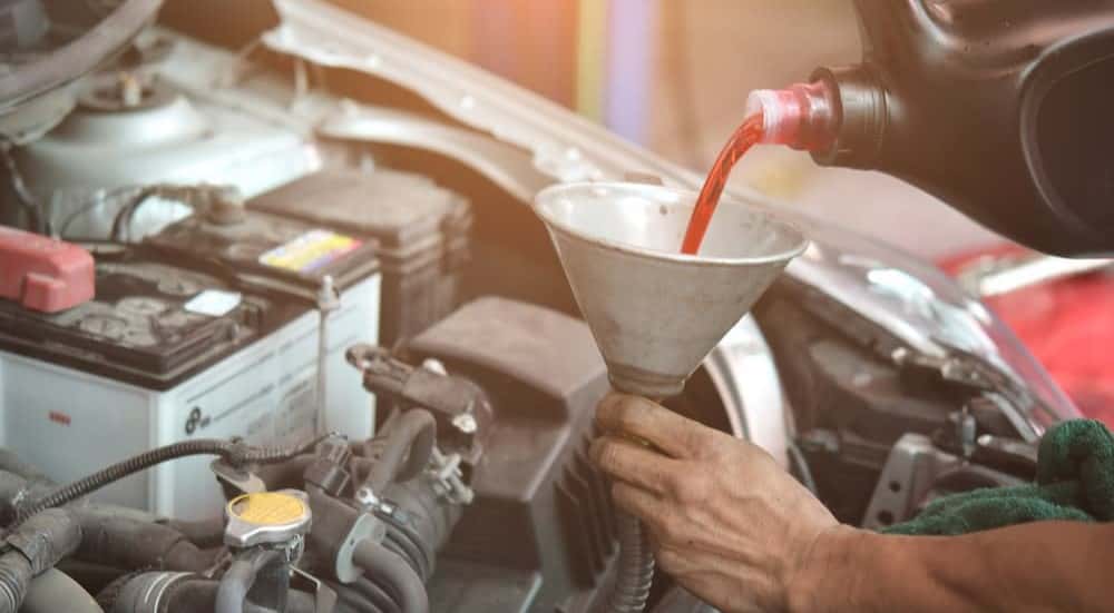 A technician pouring transmission fluid into a funnel.