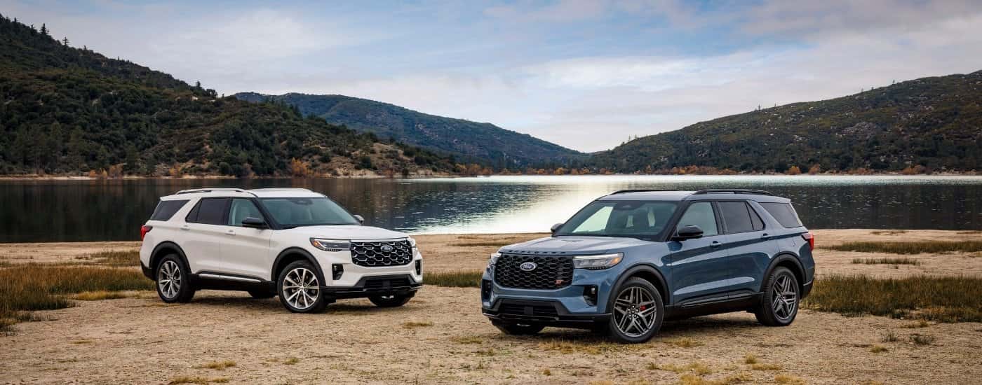 A white and a blue 2025 Ford Explorer from the front.