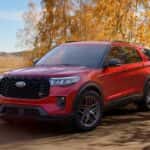 Red 2026 Ford Explorer driving on a tree-lined road