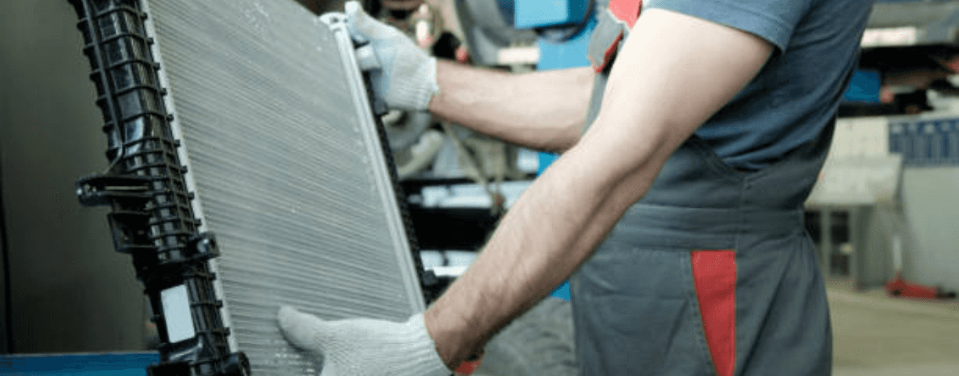A person carries a radiator to perform car radiator repair near Lawrenceville