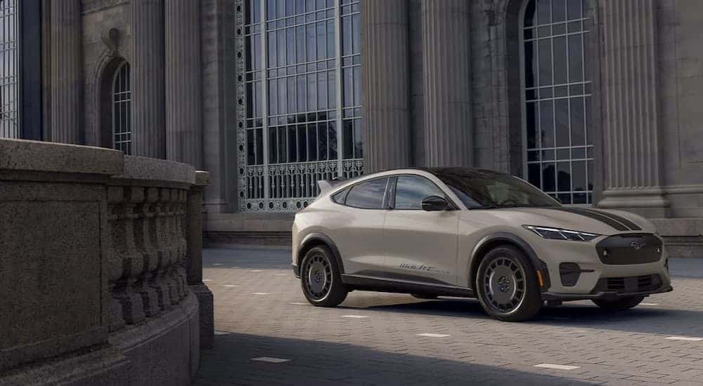 A tan 2025 Ford Mustang Mach-e parked near a stone building.