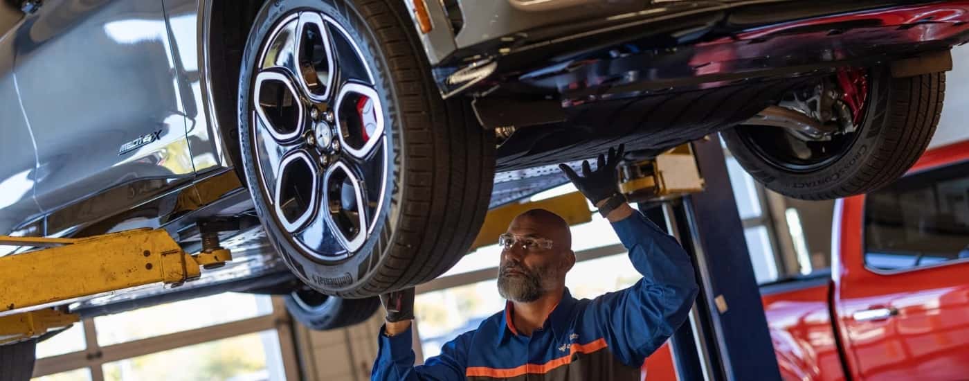 A mechanic looking underneath a vehicle on a lift
