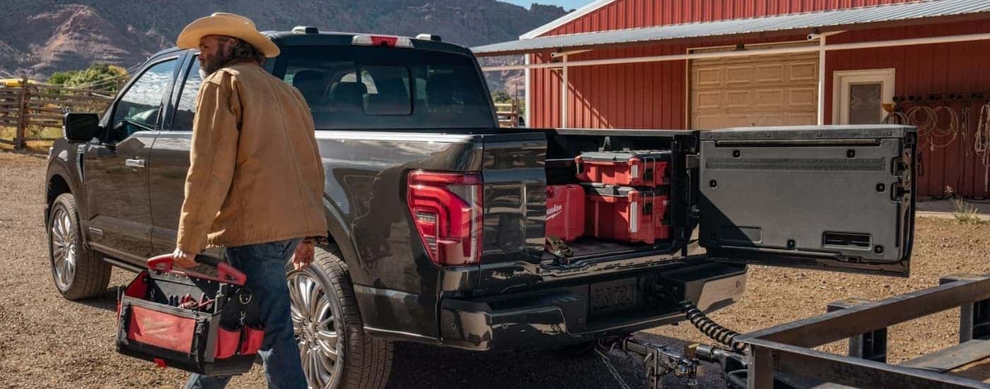A person walking near the bed of a black 2026 Ford F-150.