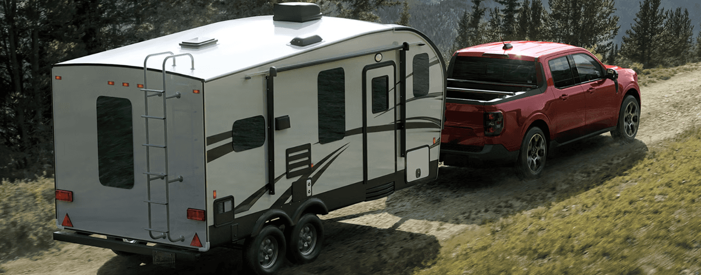 Red 2026 Ford Maverick towing a camper off-road