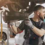 Service working draining oil from a car.