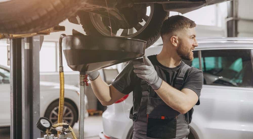 Service working draining oil from a car.