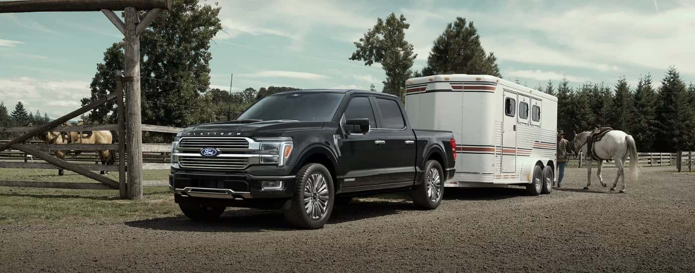 Black 2025 Ford F-150 Platinum for sale near Covington parked off-road and towing a camper.