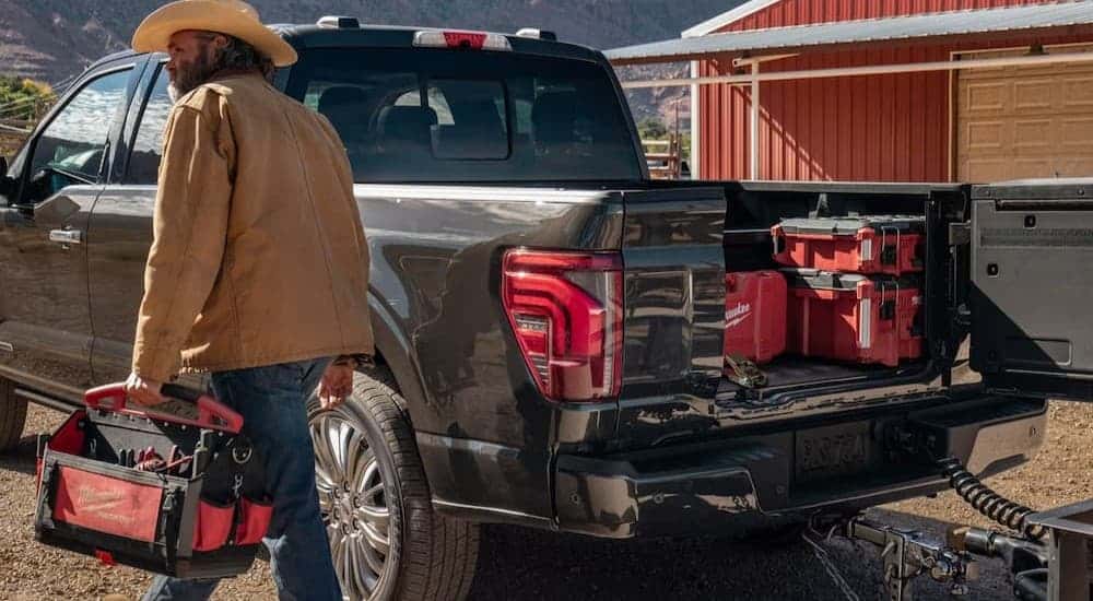A person walking near the bed of a black 2026 Ford F-150.