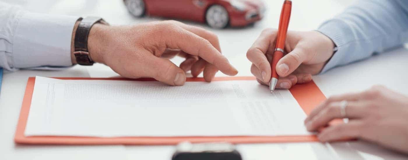 Close-up of a person signing a Ford lease on a clipboard.