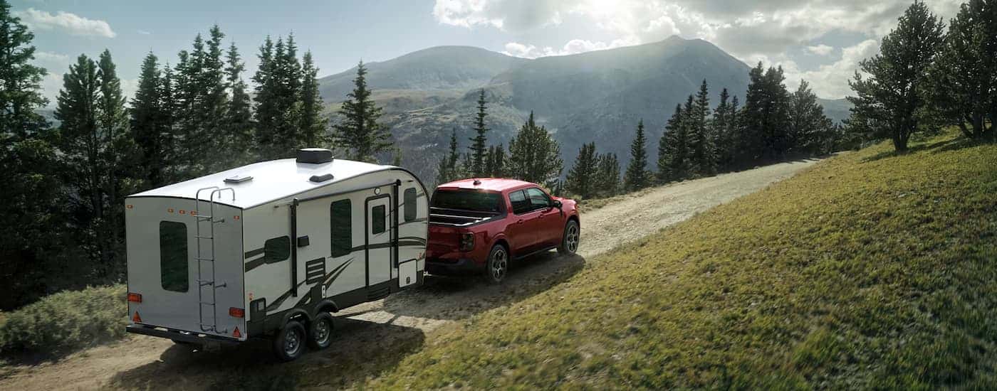 A red 2026 Ford Maverick towing a camper