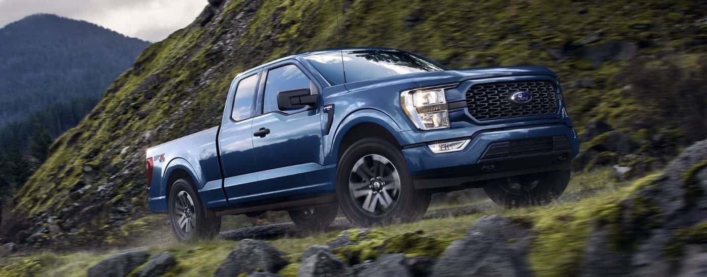 Blue 2023 Ford F-150 STX driving off-road