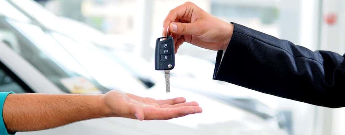 A key fob being handed to another hand.