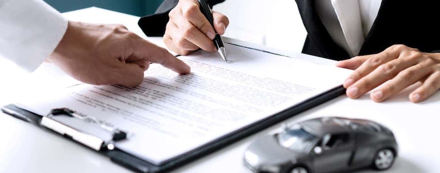 Close-up of a person signing a lease on a clipboard.