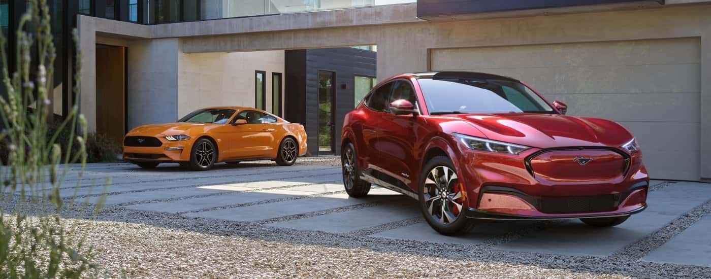 A red 2021 Ford Mustang Mach-E parked next to an orange 2021 Ford Mustang GT