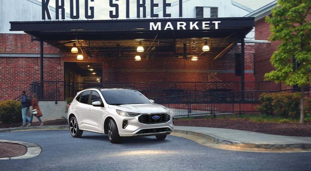 A white 2023 Ford Escape ST-Line parked outside a market