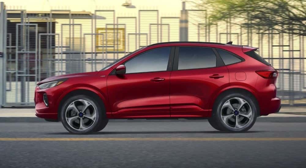 A red 2023 Ford Escape ST-Line driving in a city
