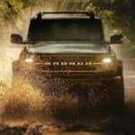 A green 2026 Ford Bronco off-roading in mud
